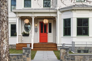 The front porch of an Italianate home in Cambridge, Mass., with an orange front door, geometric hanging lanterns, and Marvin Ultimate Double Hung G2 windows.