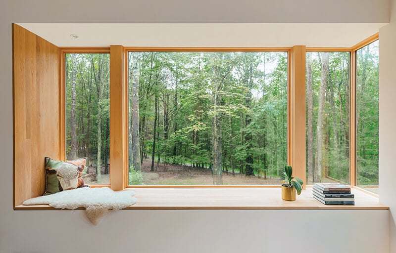 Picture windows and a corner window create a window seat that captures forest views.