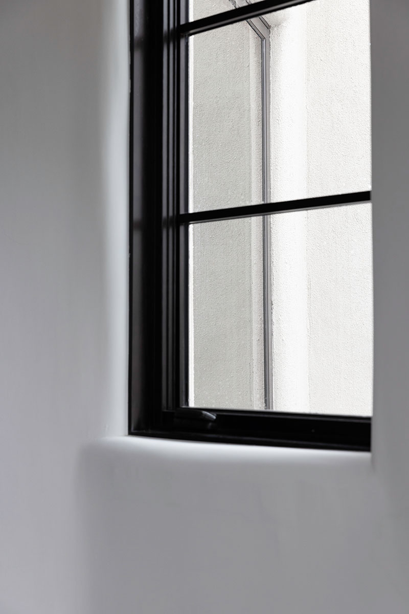 A close-up of a Marvin Ultimate Casement Narrow Frame window in Espresso stain with SDLs.