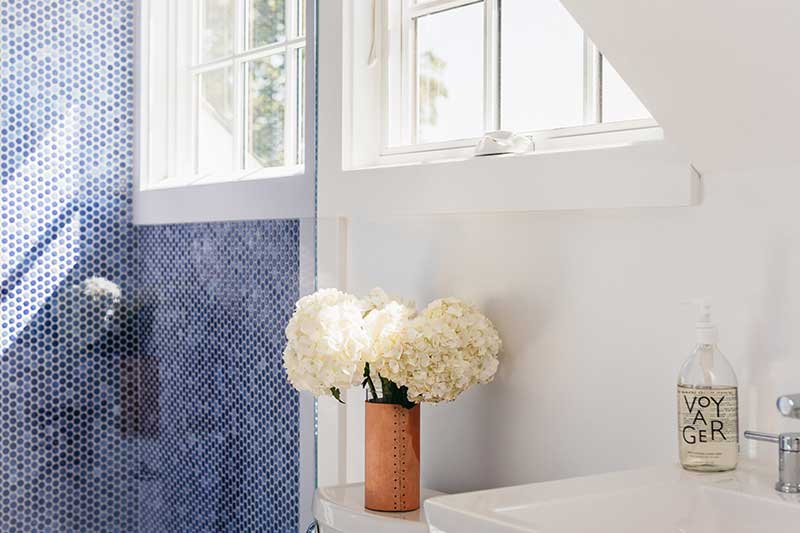 A close up of shower tile, Marvin Elevate Awning windows and sink in Liz Joy’s Connecticut home.