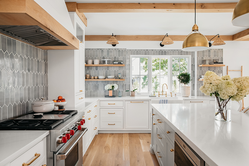 The kitchen in Liz Joy’s remodeled home, featuring exposed beams, white countertops and cabinets, and Marvin Elevate Casement windows.