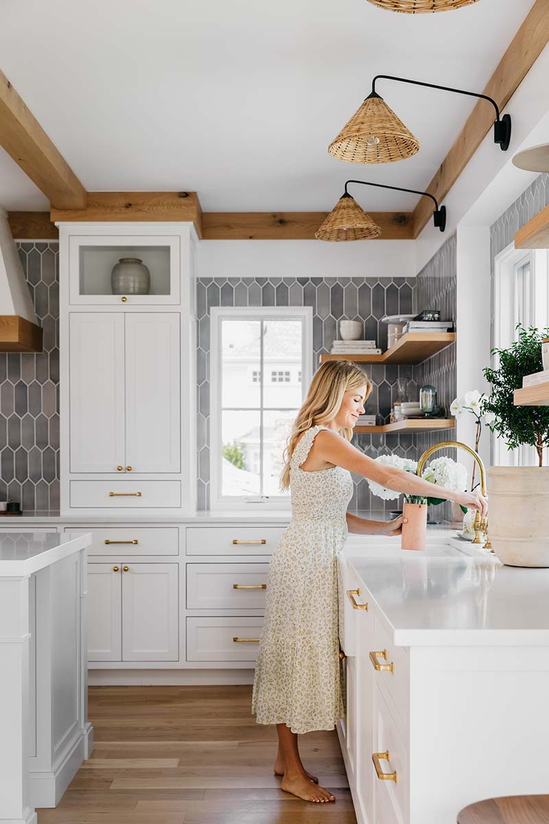 Liz Joy standing at the farmhouse sink in her remodeled kitchen, featuring Marvin Elevate casement windows.