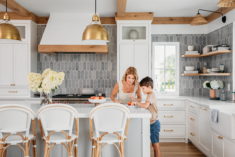 Liz Joy in the kitchen with her son, featuring exposed beams, white countertops and cabinets, and Marvin Elevate Casement windows.