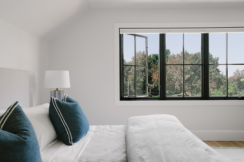 A bedroom in a modern farmhouse featuring Marvin designer black casement windows.
