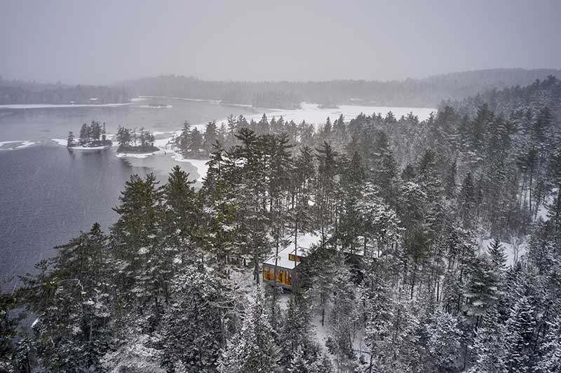 Aerial view of a remote cabin among snowy trees in Maine, featuring Marvin Ultimate windows and doors.