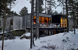 Modern cabin featuring Marvin Ultimate windows and doors, nestled in a forest in remote Maine in winter.