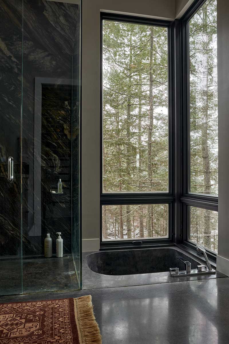 A bathroom featuring Brazilian marble and Marvin Ultimate awning and picture windows surrounding a sunken tub.