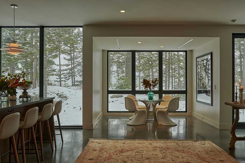 A modern kitchen and dining area looking out on a snowy landscape through Marvin Ultimate windows.