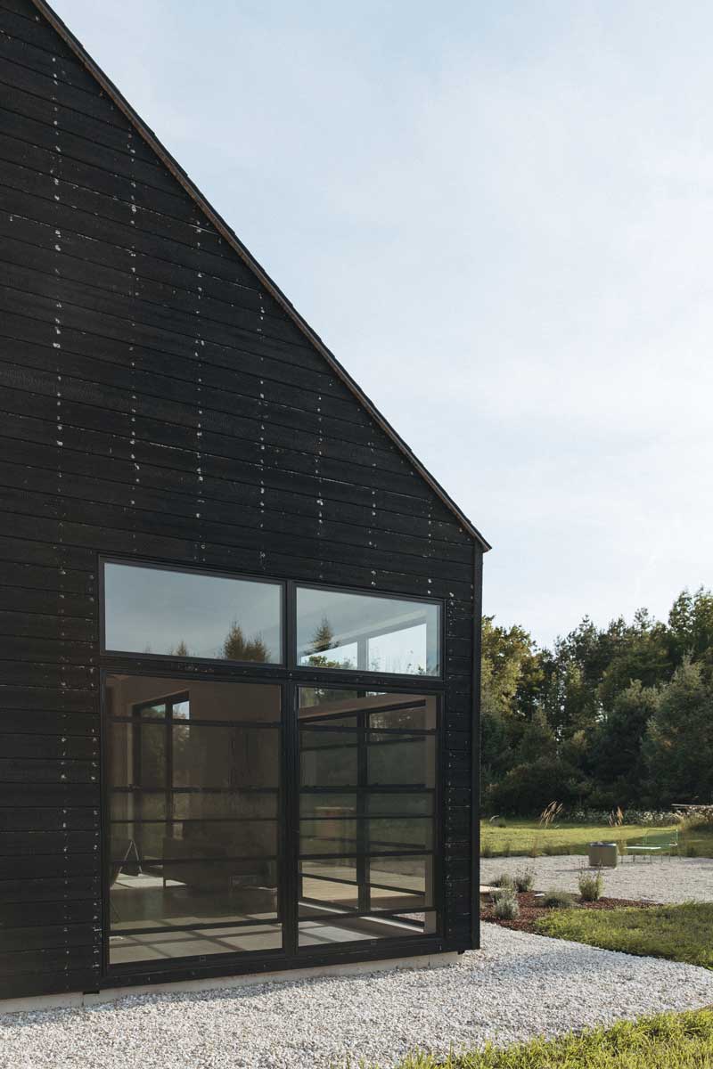 A side view of Svart Hus showing the conection between the one building with black-stained shiplap siding and the other with contrasting lighter stained wood.