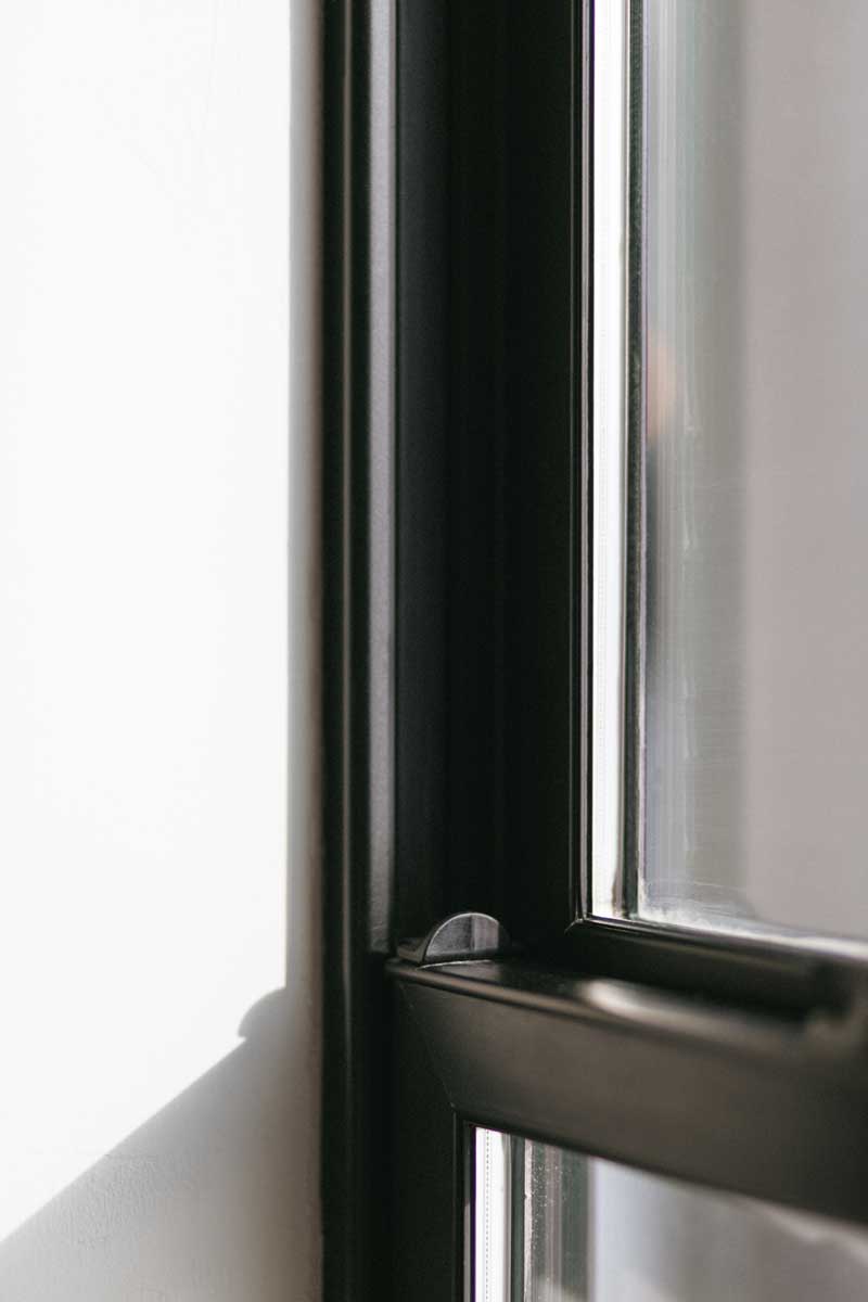 A close up detail of a Marvin Essential double-hung window showing the locking mechanism on the frame at Svart Hus in Door County, Wisconsin. 