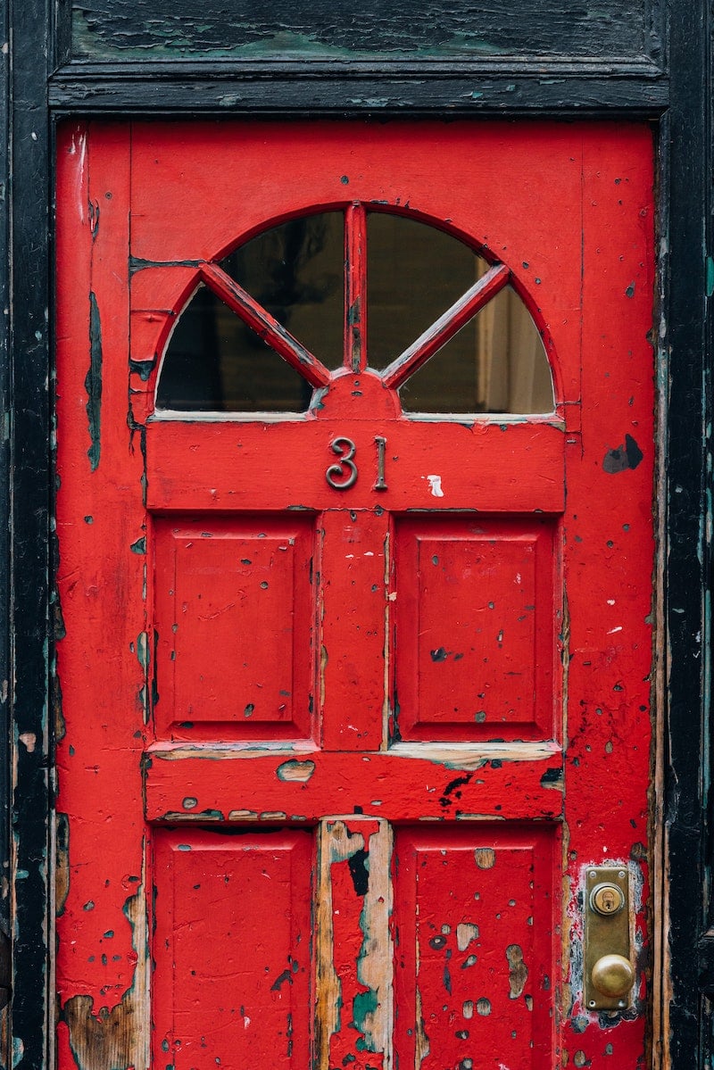 An old red front door with chipping paint.