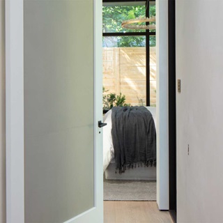 A white TruStile frosted glass panel door leading into a bedroom at Stay Bungalow in Austin, Tx.