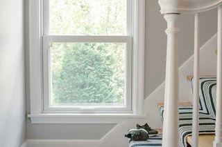 A white double hung window in a stairwell.
