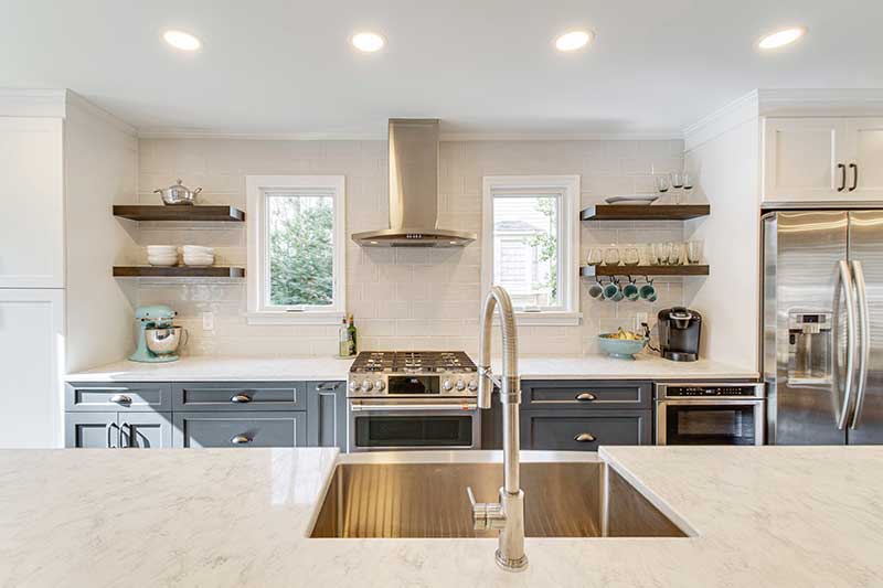 A modern kitchen featuring open shelves, white countertops, dark cabinets and Marvin casement windows.