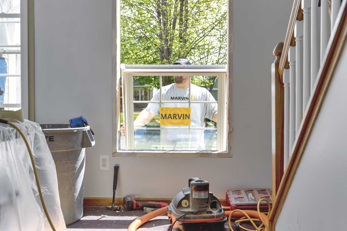 A man holding a Marvin window outside a home as he gets ready to install it. 