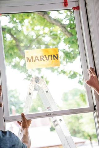 A man holding a Marvin window outside a home as he gets ready to install it. 