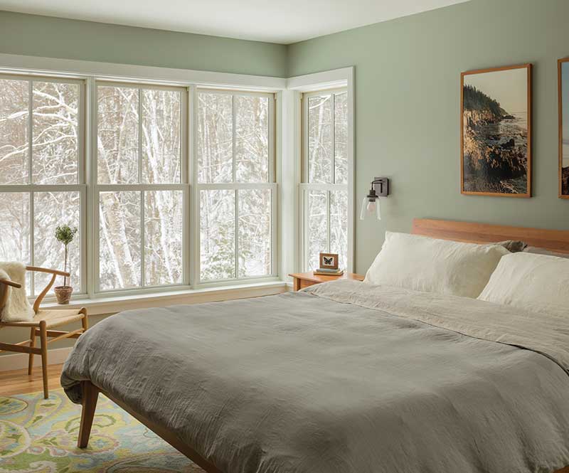 A farmhouse bedroom in winter with white Marvin Elevate double hung windows with simulated divided lites.