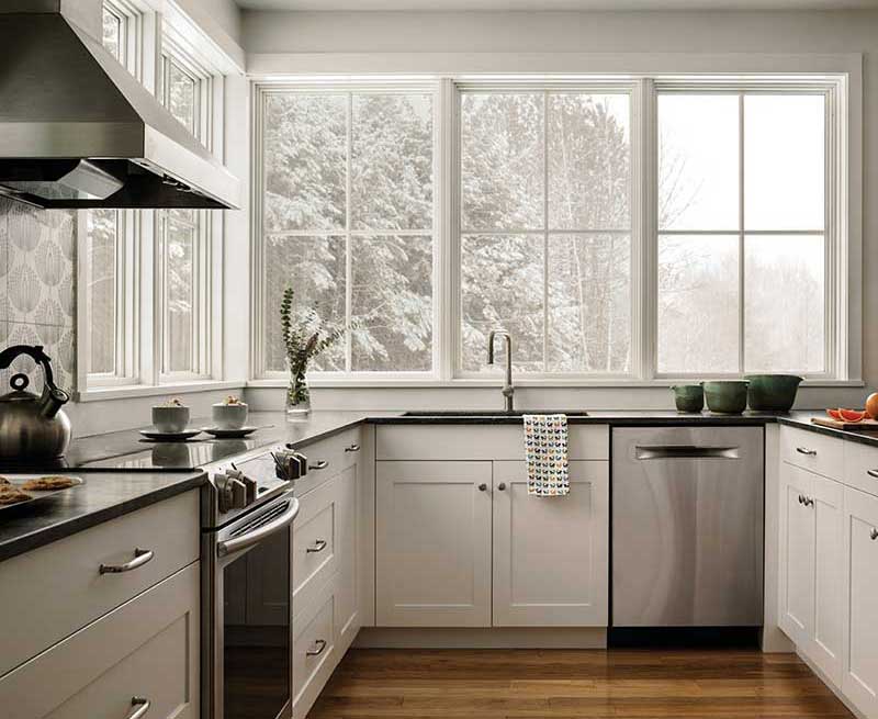 A modern farmhouse kitchen in winter with white Marvin Elevate picture windows with simulated divided lites.