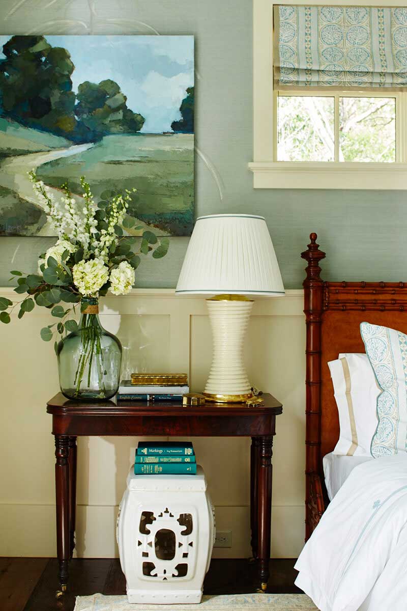 Nightstand with lamp and flowers next to bed