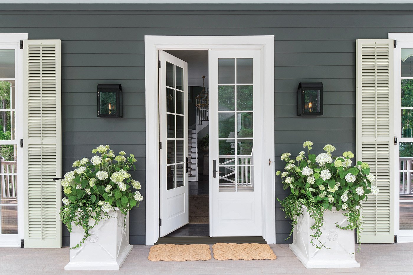 A white Marvin Ultimate Inswing French Door G2 on the porch of the Southern Living Idea House between two flower boxes. 