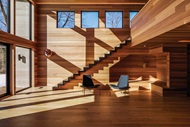 The sitting room of a wooden home with a staircase