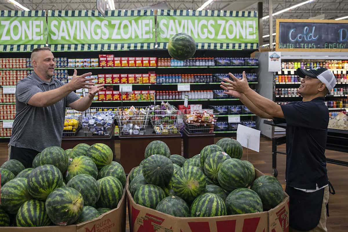 Two workers in Warroad grocery store tossing a watermelon