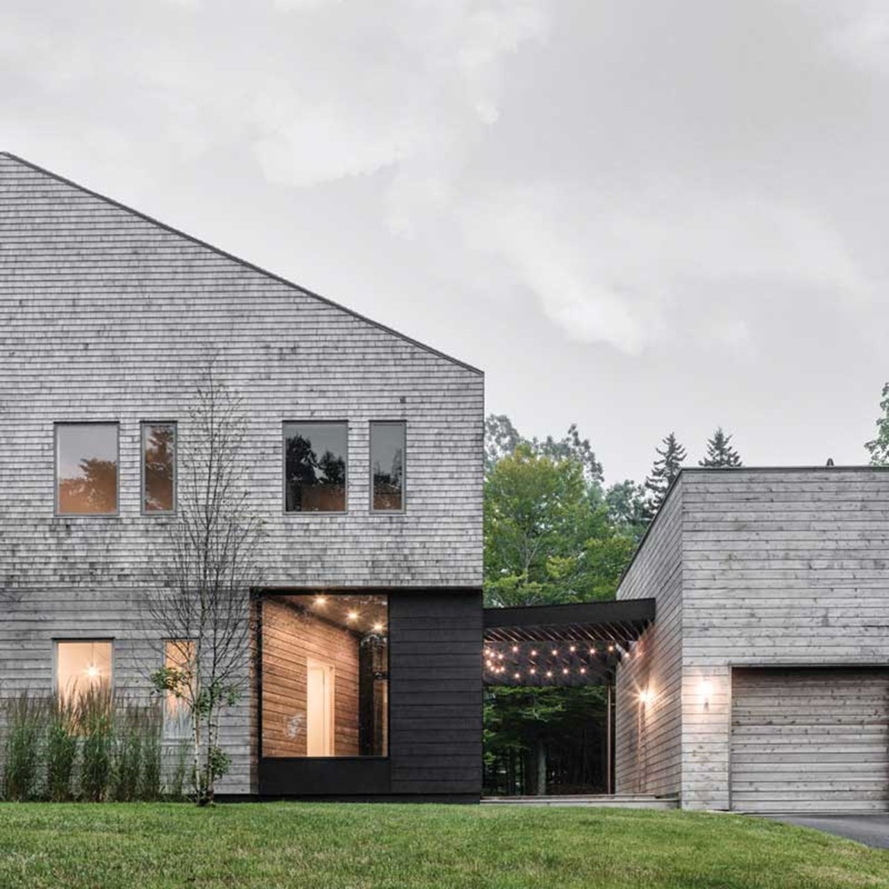 Polygon shaped home with grey wood siding and marvin windows