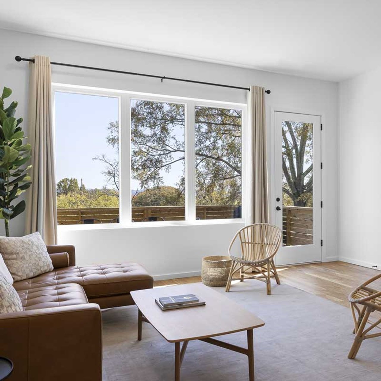 A spacious modern living room with an Essential casement picture window and a brown leather couch