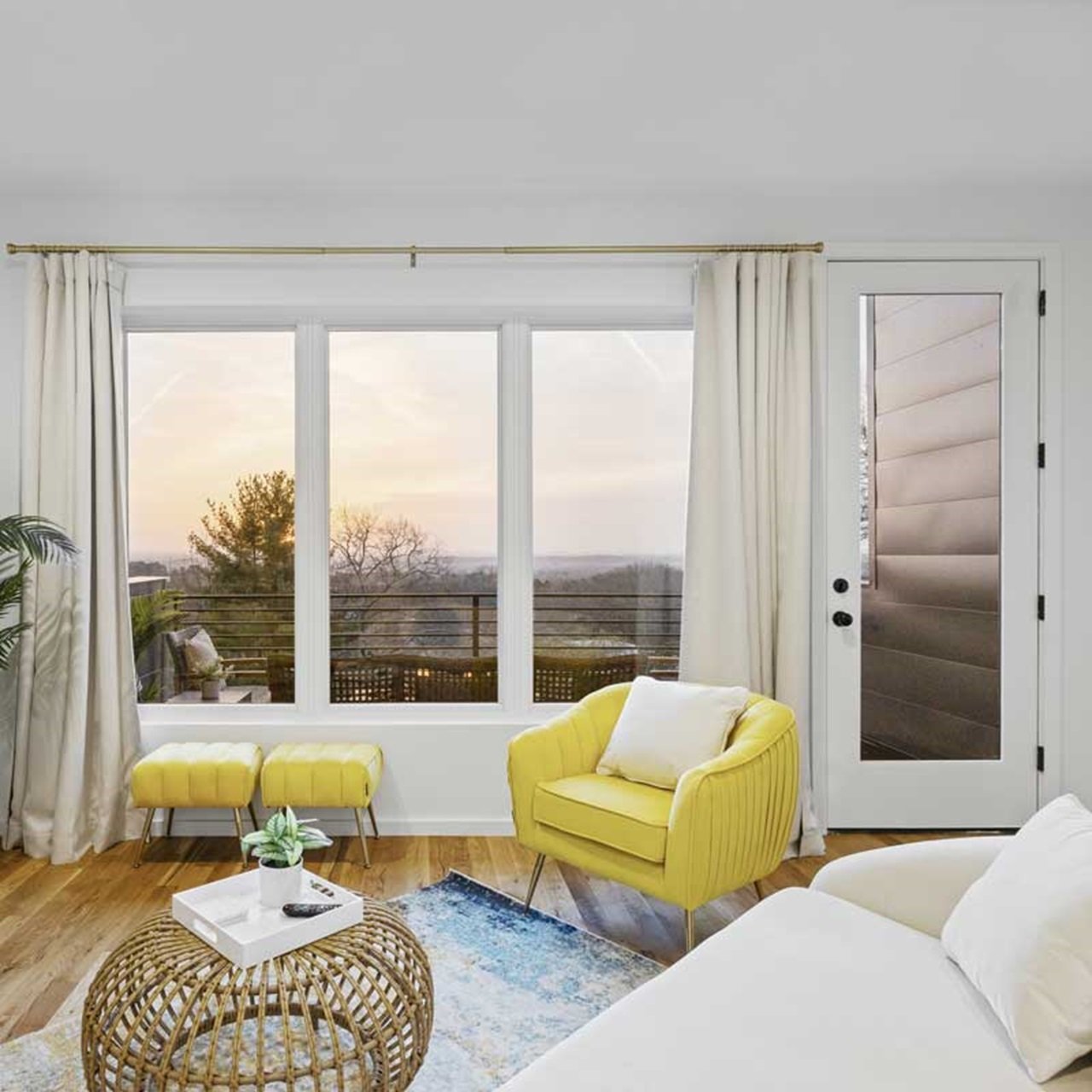 A modern living room with an Essential casement picture window overlooking a sunset