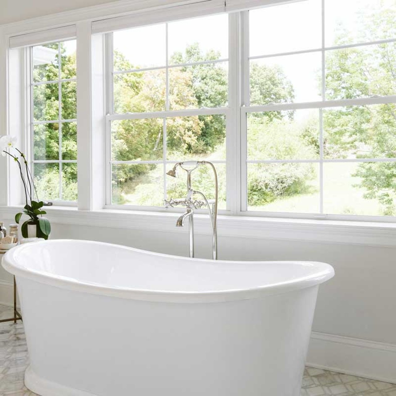 Bathroom with white free standing bathtub and double hung windows