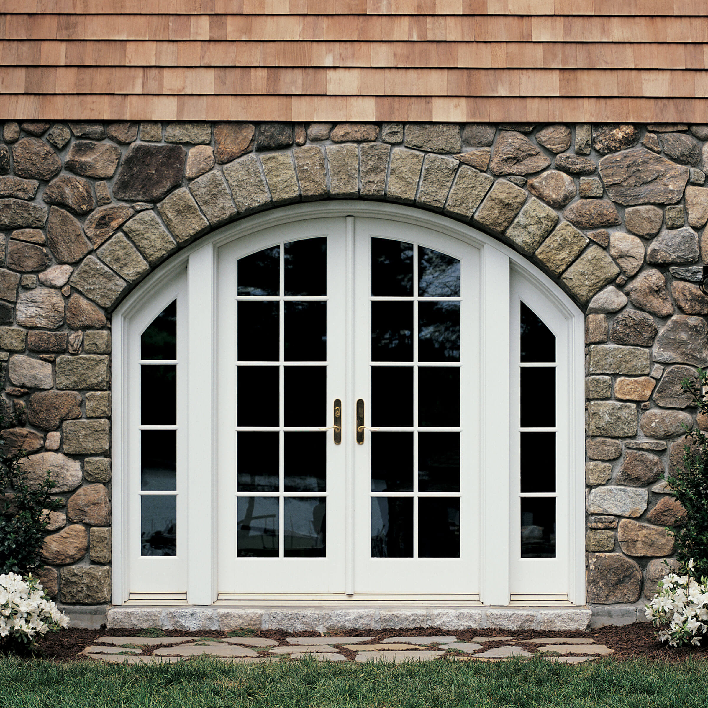 Stone-Faced Exterior View Of House With Signature Ultimate Swinging Arch Top French Door 