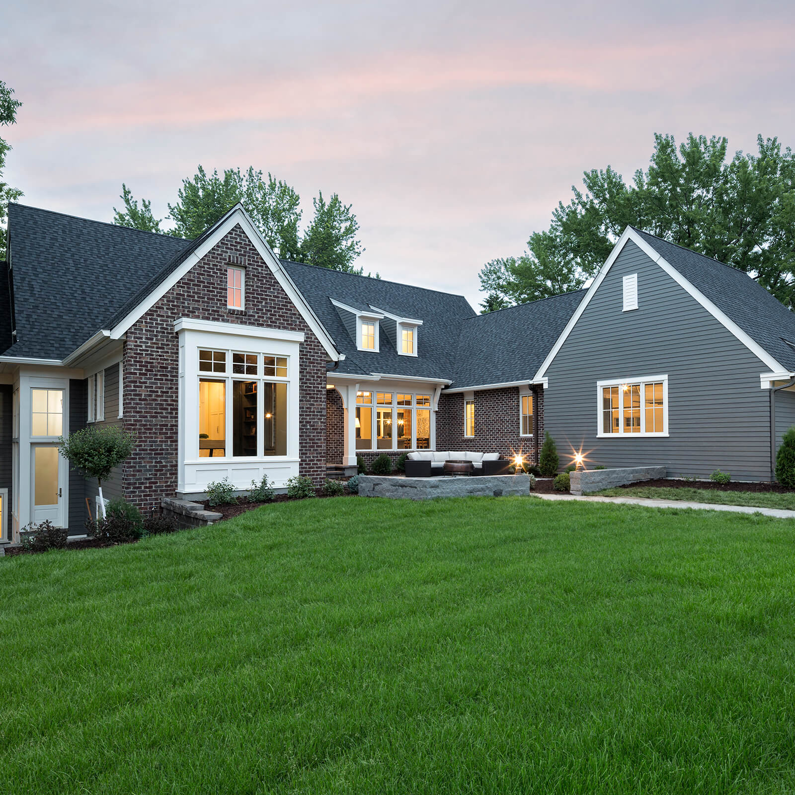 Exterior of home with blue siding and brick facade with Marvin Signature Ultimate Casement Windows