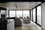 Open plan kitchen and living room with large modern windows with coastal view
