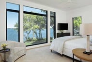 Bedroom with large modern windows looking out to a lake