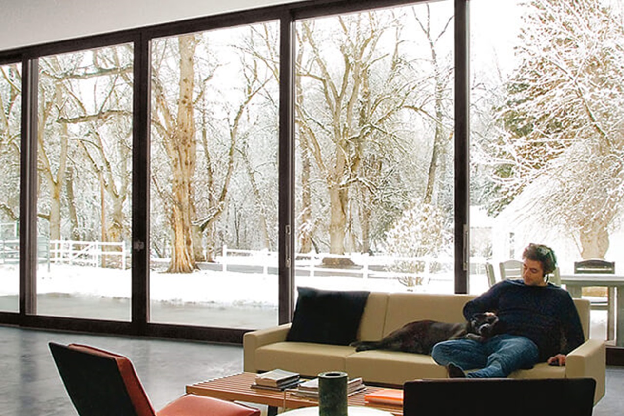 Man In Living Room With Snowy Scene Outside Through Signature Ultimate Lift And Slide Door