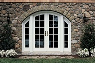 Stone-Faced Exterior View Of House With Signature Ultimate Swinging Arch Top French Door