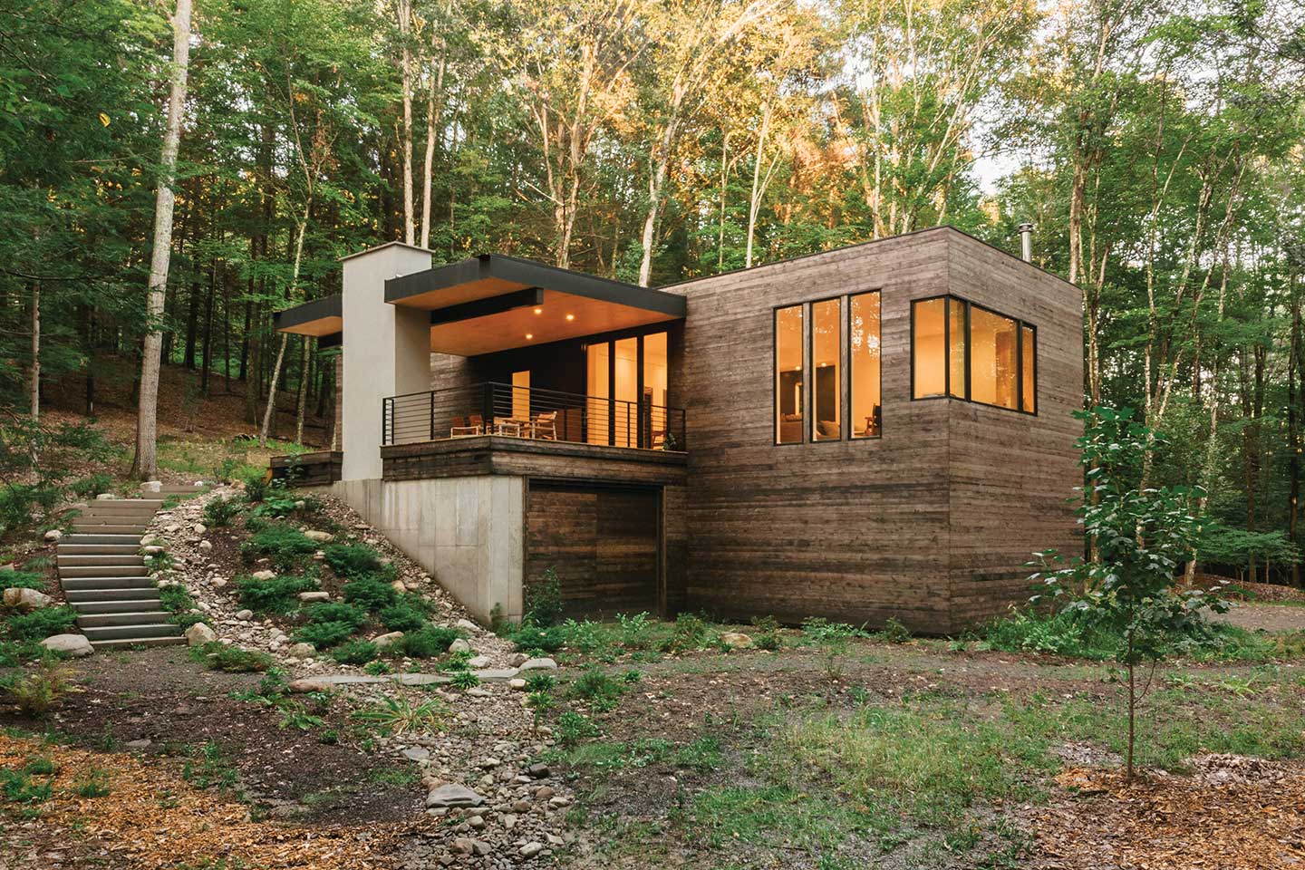 An exterior photo of a contemporary home built into a hillside surrounded by trees in New York’s Hudson Valley, featuring Marvin Ultimate windows.