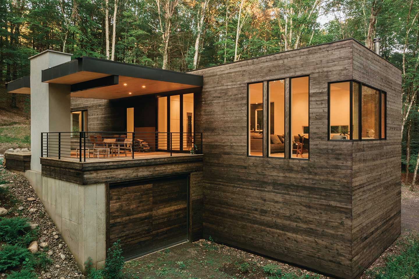 An exterior photo of a contemporary home built into a hillside surrounded by trees in New York’s Hudson Valley, featuring Marvin Ultimate windows.