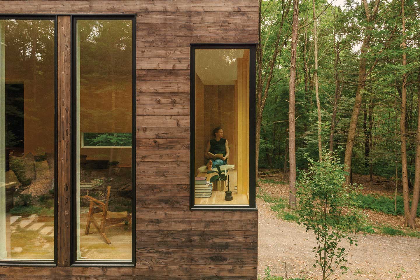 Architect Marica McKeel sitting in the window nook of her contemporary home in Hudson Valley, New York, featuring a Marvin Ultimate Corner window.