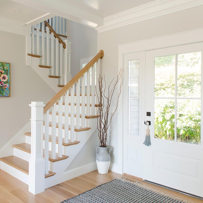 The front entrance and staircase in a Dutch Colonial home in Westerly, Rhode Island, featuring a Marvin door.