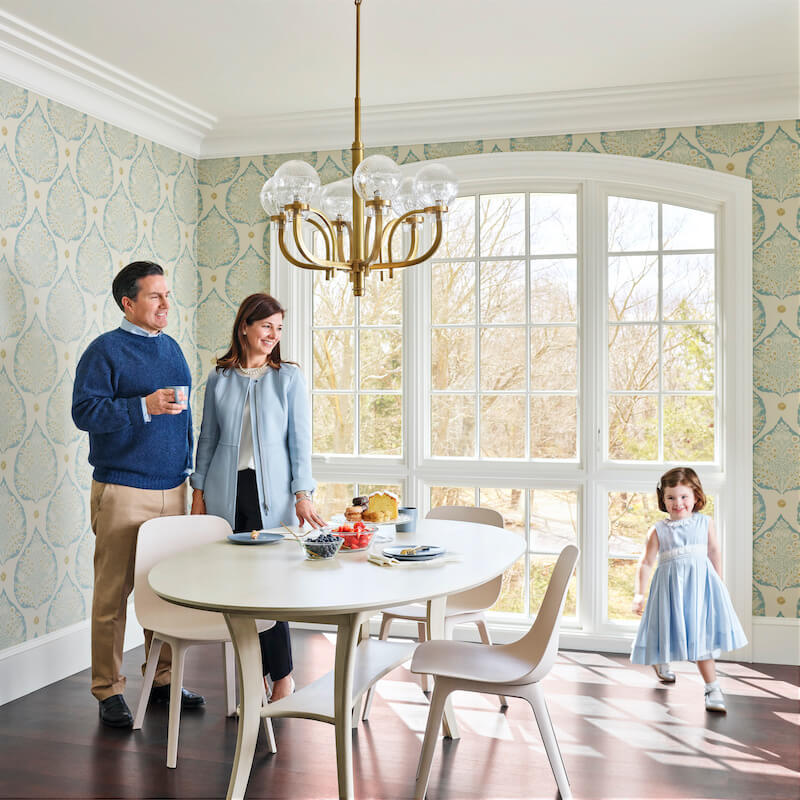 A family in a dining area of their 1890s Cape Ann home featuring Marvin windows.