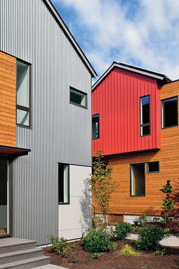 A detail of the exterior of Grow Community with a pop of red, natural wood, and metal siding. Different sized Marvin Elevate windows were incorporated to maximize natural light.