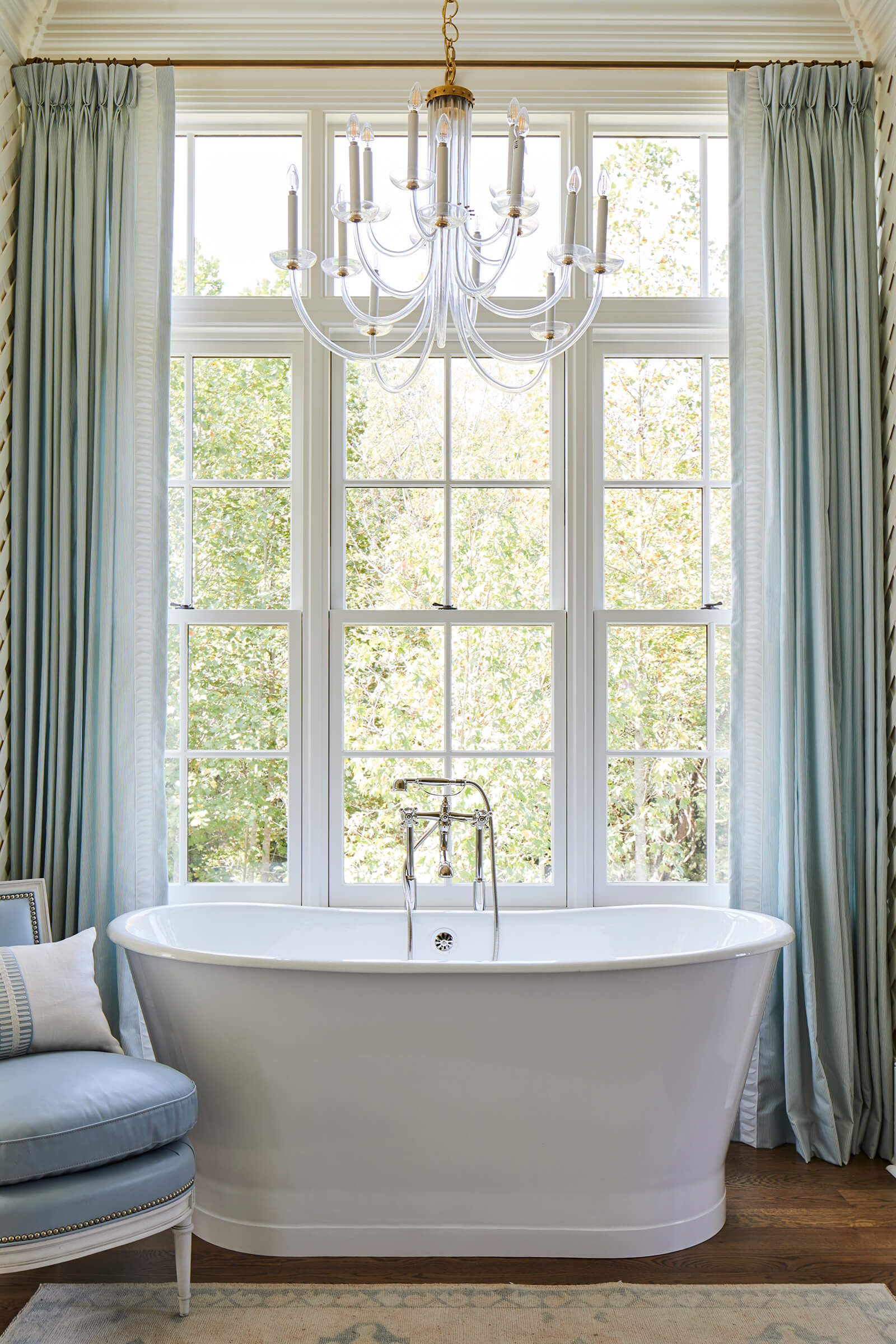 A large bathtub with Marvin double hung windows behind it.