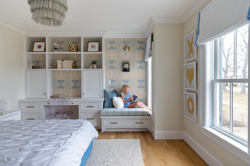 A young girl reads in a reading nook of her room next to a Marvin Elevate double hung window.
