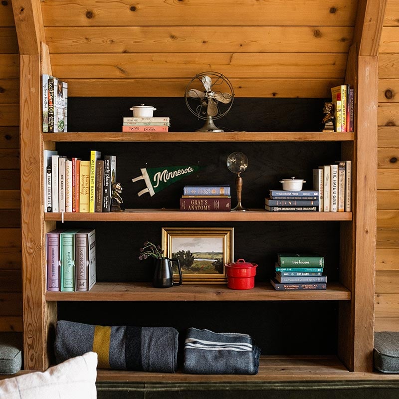 A bookshelf filled with books and antiques in The Minne Stuga, a cabin in the Northwoods.