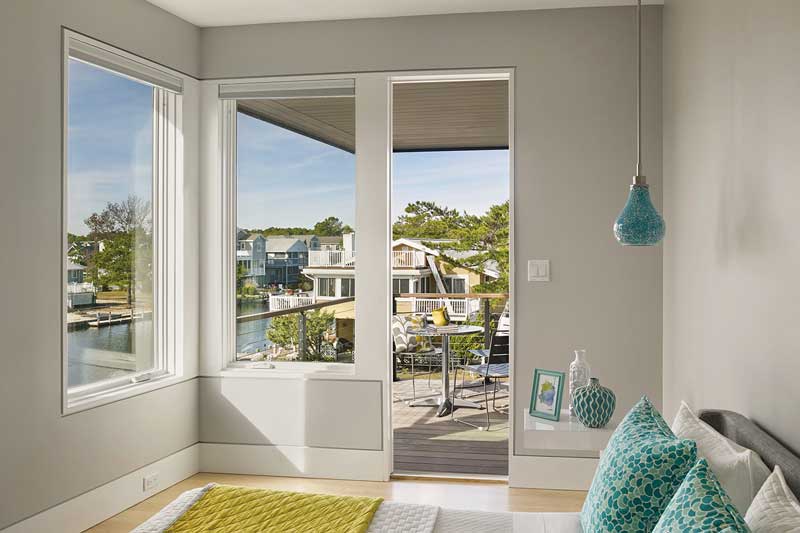 A bedroom in a modern beach house featuring Marvin Elevate Casement windows and an Elevate Outswing French door.