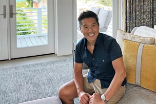 Vern Yip sitting on couch in front of large Marvin Windows at his beach home