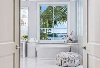A bathroom with a free standing tub a a Marvin coastline direct glaze narrow frame window above the tub