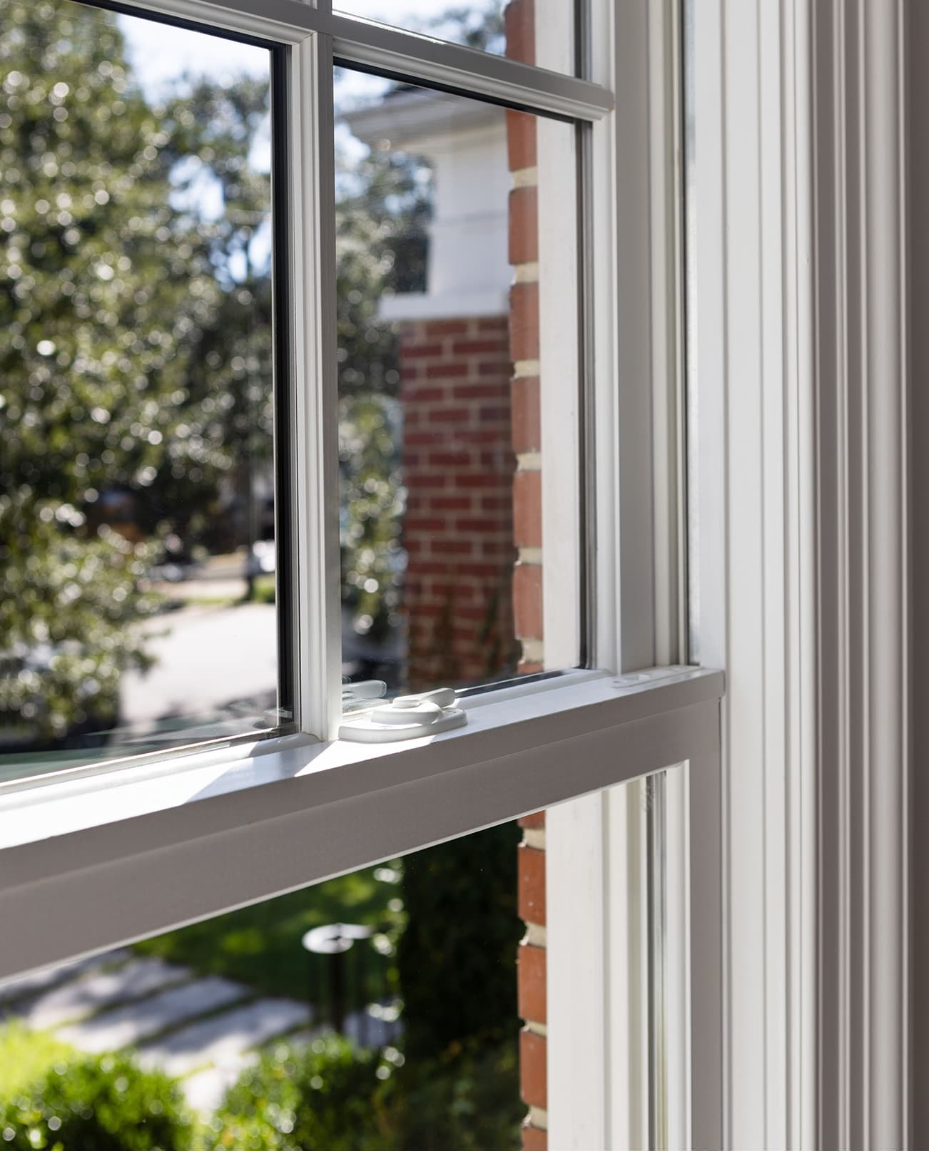 Close up interior view of a white Marvin Elevate Double Hung window check rail and cam lock with divided lites.