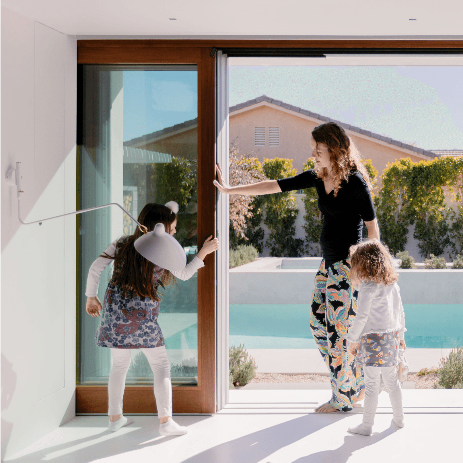 A woman opens a Marvin Ultimate Lift and Slide door with two little girls near.